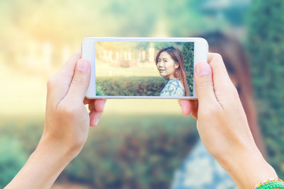 Midsection of woman photographing with mobile phone