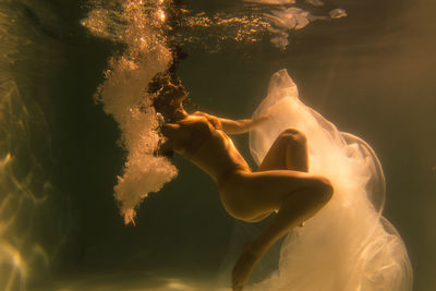 Woman with curtain swimming in pool