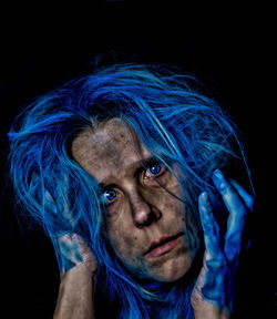 Close-up portrait of woman wearing mask against black background