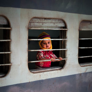 Portrait of cute girl looking through window