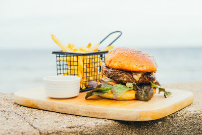 Close-up of burger served on cutting board at beach