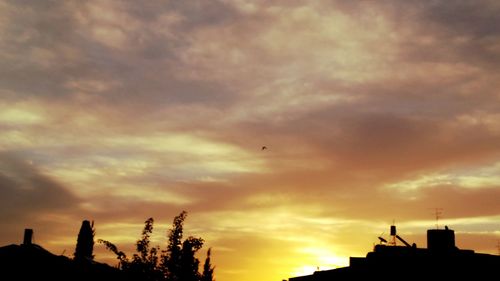 High section of silhouette buildings against dramatic sky
