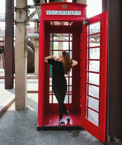 Young woman standing in telephone booth