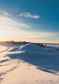 Scenic view of snow covered land against sky during sunset