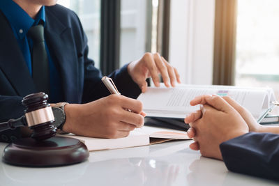 Midsection of lawyer discussing with customer on table