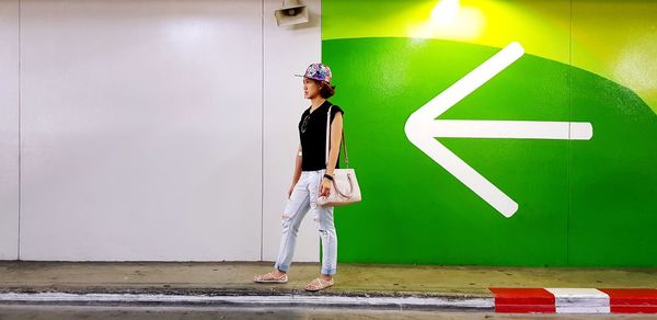 Portrait of young woman standing against wall