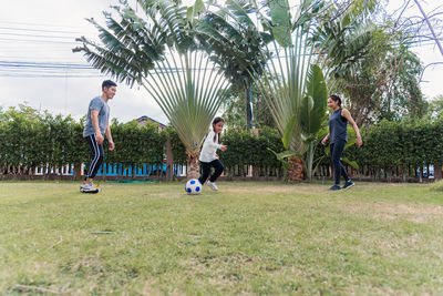 People playing soccer on field against trees