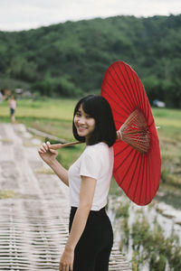 Portrait of smiling woman with umbrella standing on boardwalk