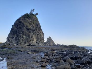 Rock formations on shore against clear sky