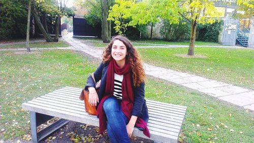 Portrait of smiling young woman sitting at park