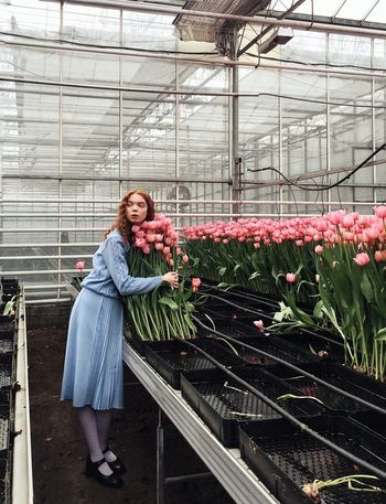 WOMAN STANDING IN A GREENHOUSE