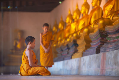 Side view of boy praying in buddhist temple