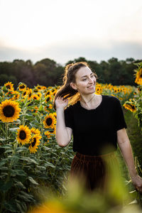 Young woman standing on sunflower field