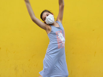 Full length of woman standing against yellow wall