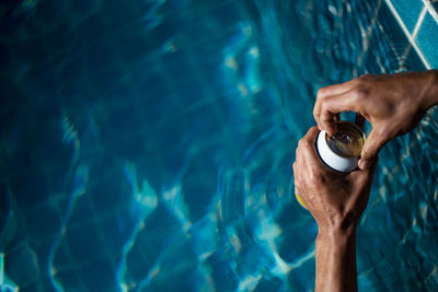 Selective focus white beer can in hand. man is soaking in the pool with an open beer 