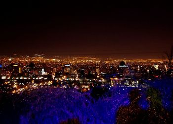 High angle view of illuminated city buildings against sky at night