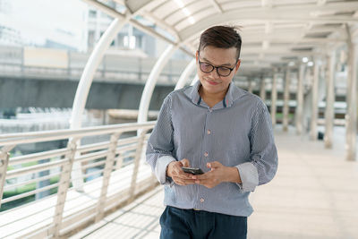 Man using smart phone on elevated walkway