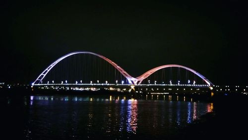 View of illuminated bridge over river at night