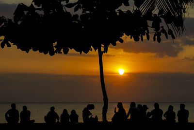 Silhouette people at beach against sky during sunset