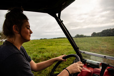 Side view of woman in car against sky