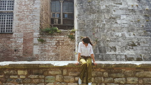 Woman sitting on retaining wall