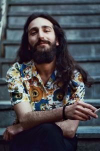 Thoughtful man smoking cigarette while sitting outdoors