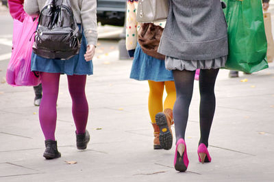 Low section of women walking on sidewalk