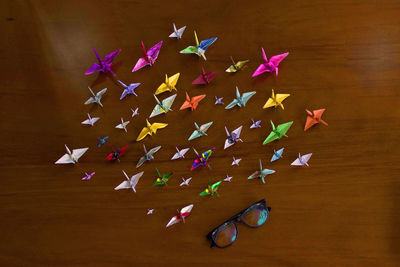 High angle view of multi colored origami and eyeglasses on table