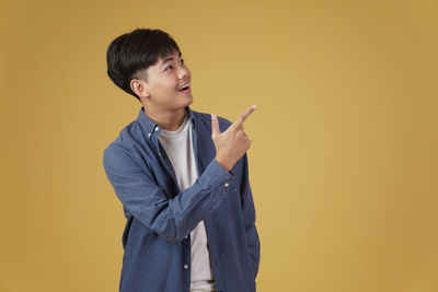 Portrait of boy standing against yellow background