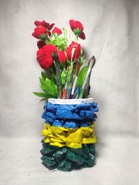 Close-up of multi colored flowers in vase on table against wall