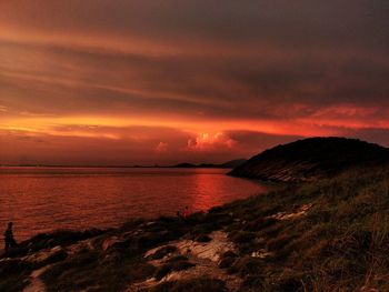 Scenic view of sea against dramatic sky during sunset