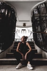 Portrait of smiling young woman sitting against built structure