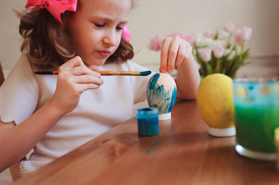 Girl painting eggs on table