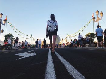 Rear view of people walking on road against sky