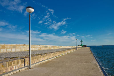 Street light on pier by sea against sky