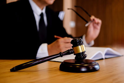 Midsection of male lawyer with gavel at desk in office