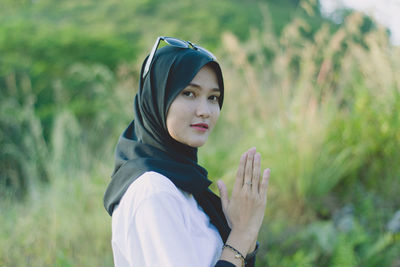 Portrait of young moslem woman pray against plants