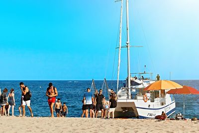 People on beach against clear blue sky