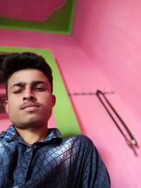 Portrait of young man looking away against wall