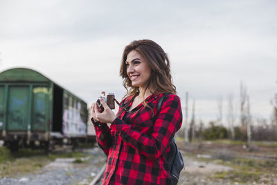 Portrait of smiling young woman standing against sky