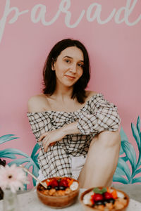 Portrait of smiling woman sitting by wall