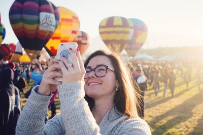 Portrait of young woman wearing sunglasses at music concert against sky