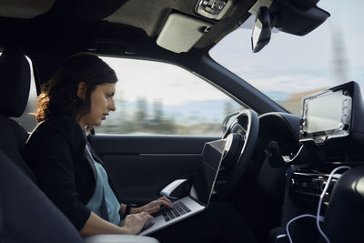 Businesswoman using laptop in driverless car