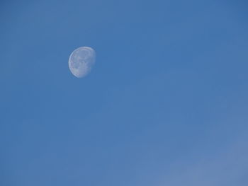 Low angle view of moon against blue sky