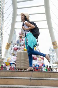 Tourist with luggage standing on steps in city during christmas