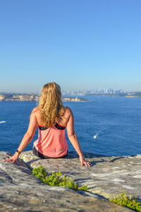 Rear view of woman looking at sea against clear blue sky