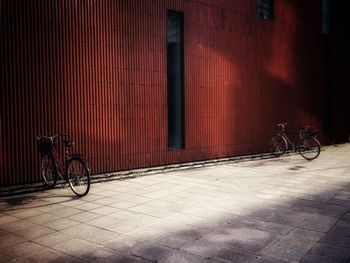 Bicycle parked on footpath against building
