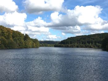 Scenic view of river by trees against sky