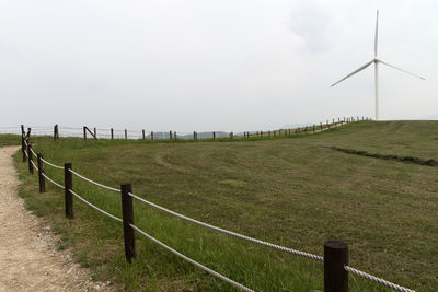 Wind power generator on field against sky