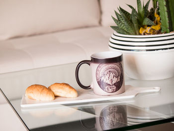 Close-up of coffee cup and croissant on table at home